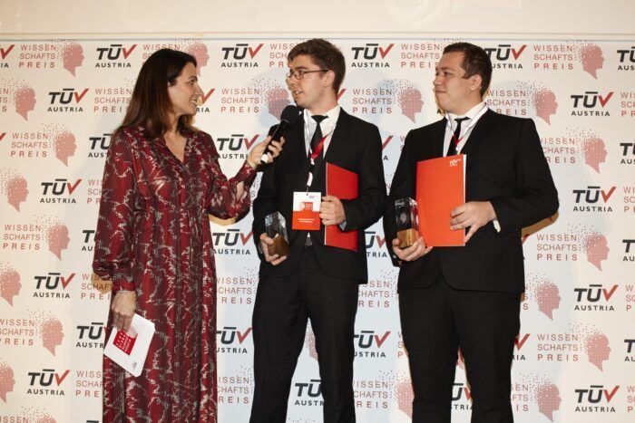 Christopher Kerl und Alexander Schuster (HTL Hollabrunn, Fachrichtung Elektrotechnik) mit Moderatorin Lisa Gadenstätter. Sie freuten sich in der Kategorie HTL Abschlussarbeiten über den Sieg beim TÜV AUSTRIA Wissenschaftspreis 2022. Sie entwickelten ein neuartiges, digitales System zur Durchführung von Atemschutzübungen bei der Feuerwehr und anderen Hilfs- und Rettungsorganisationen.